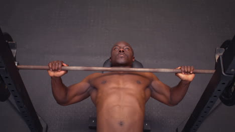 concentrated fit man holding barbell lying on exercise mat