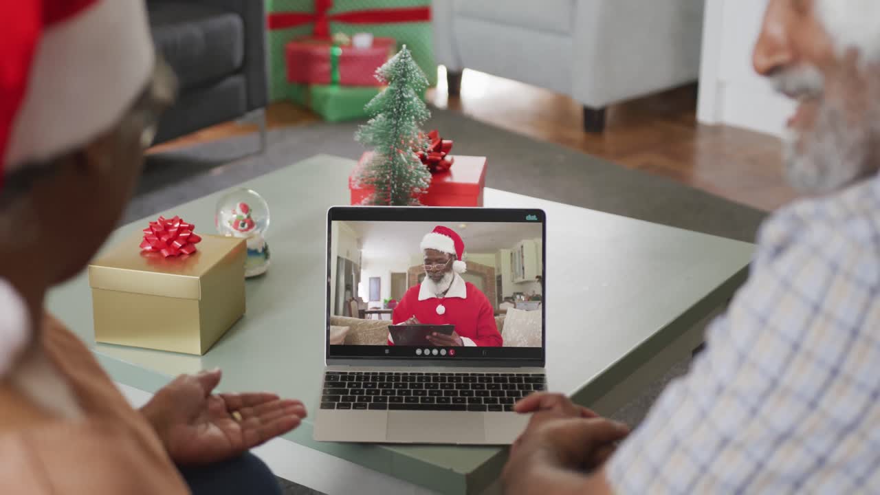 feliz pareja de ancianos afroamericanos en videollamada con santa claus en navidad