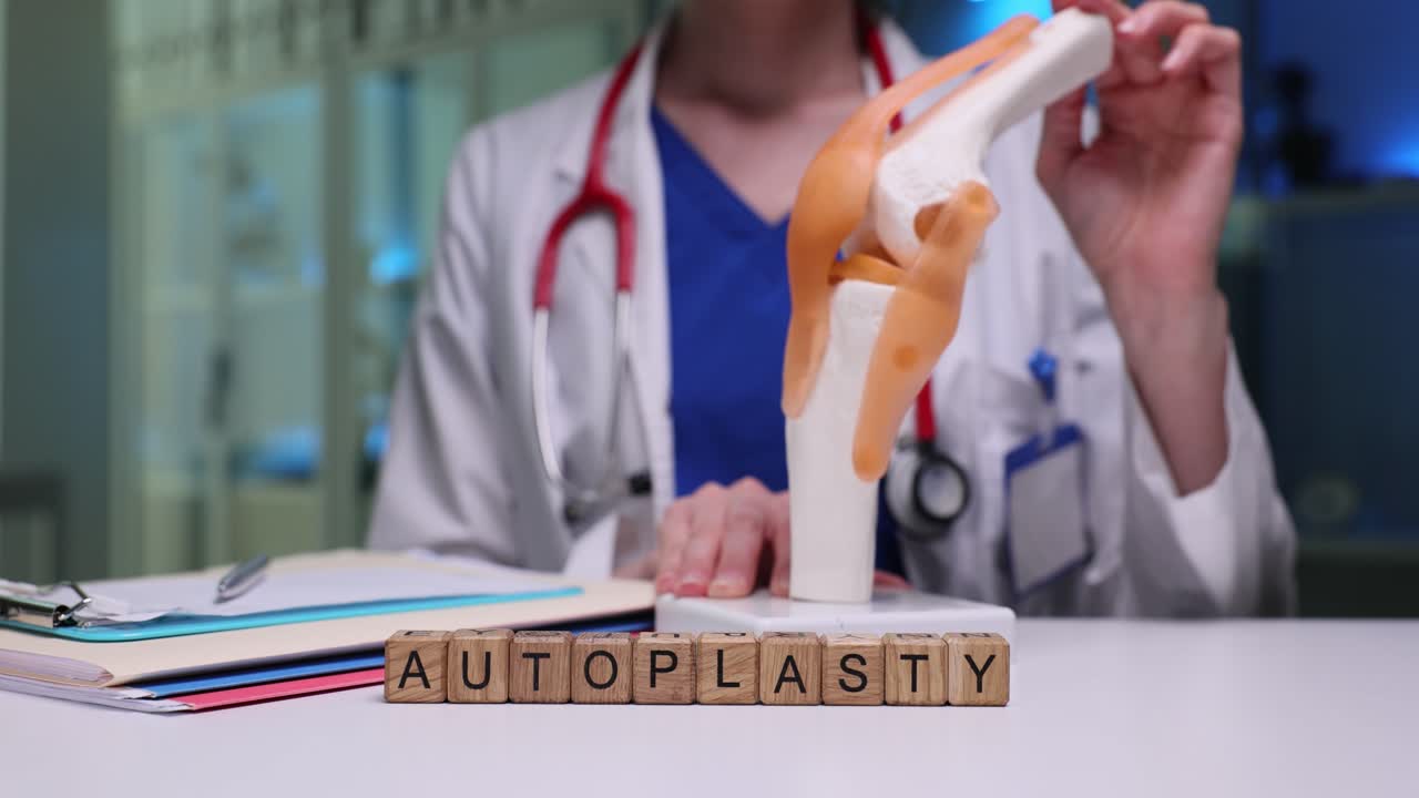 Wooden blocks spell word autoplasty near joint model on desk