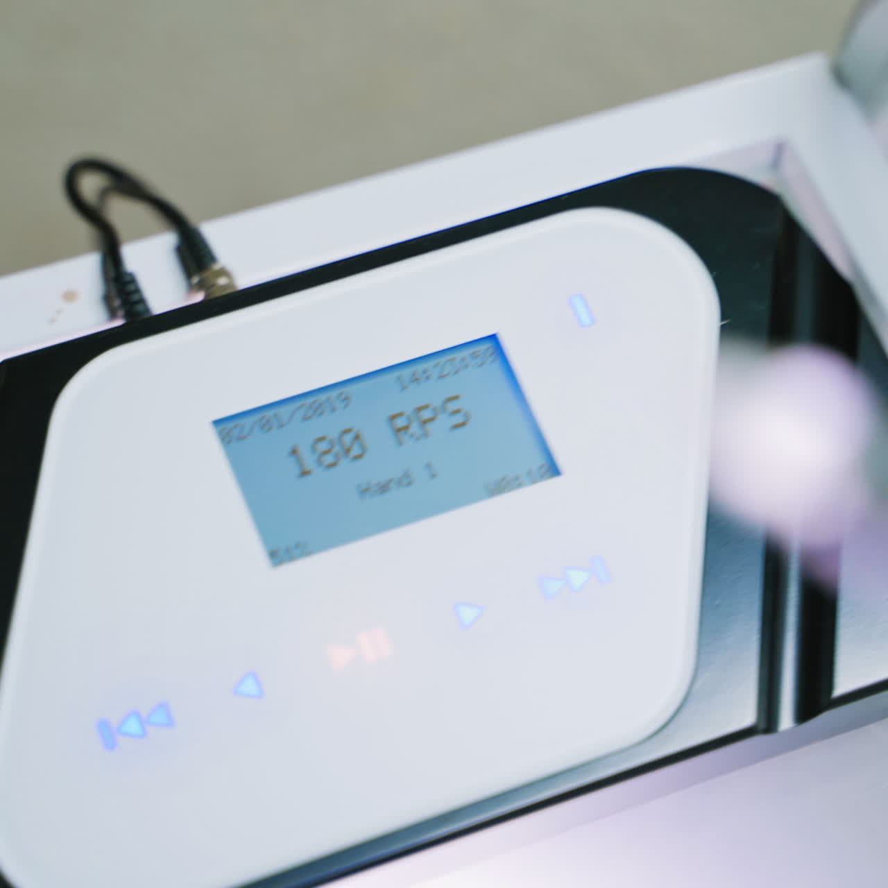 Woman's hand in white glove is switching on the tattoer machine. Modern instrument for doing permanent make-up in a beauty salon. Close-up