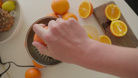 jugo de naranja fresco siendo exprimido a mano en la cocina del hogar con un exprimidor eléctrico