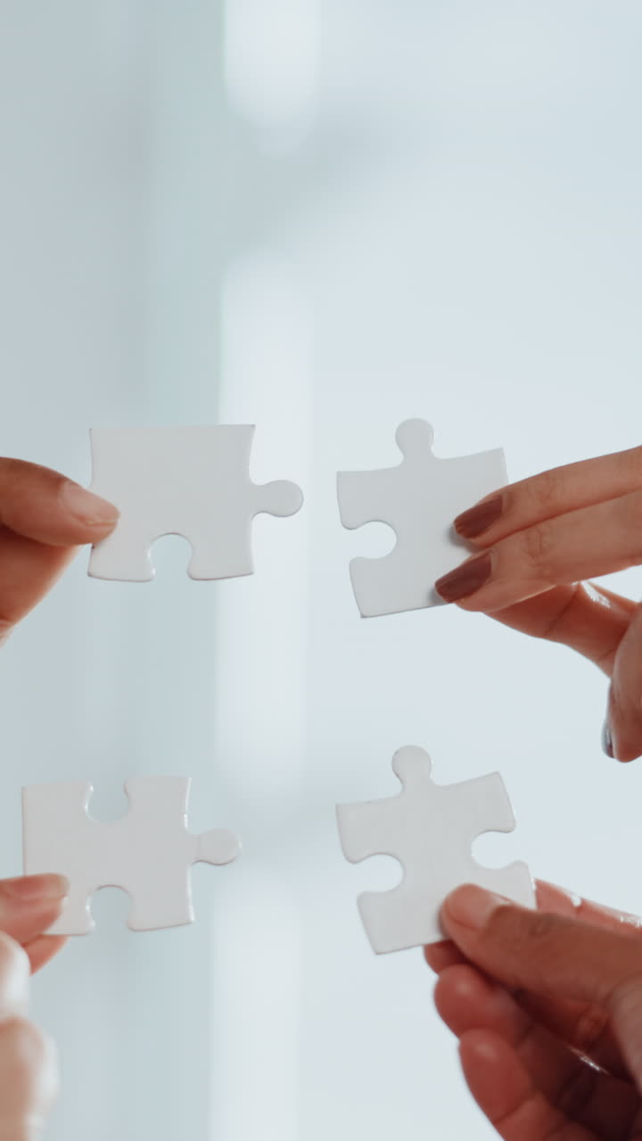 Mani che assemblano insieme i pezzi di un puzzle bianco