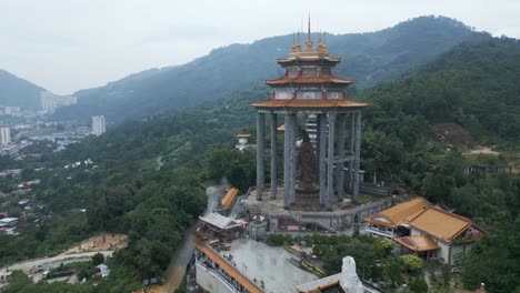 aerial of kek lok si temple penang island malaysia buddha scullpture close up drone fly above green vegetation jungle and cityscape
