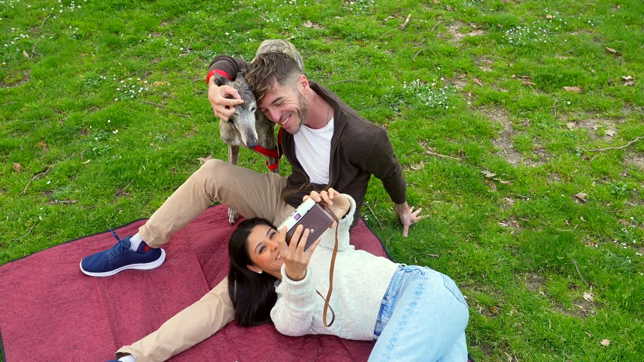 Coppia felice che si scatta selfie con il proprio cane in un parco.