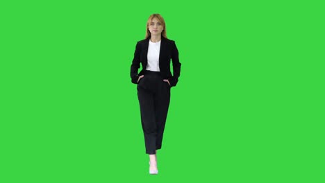 walking businesswoman with hands in pockets on a green screen, chroma key