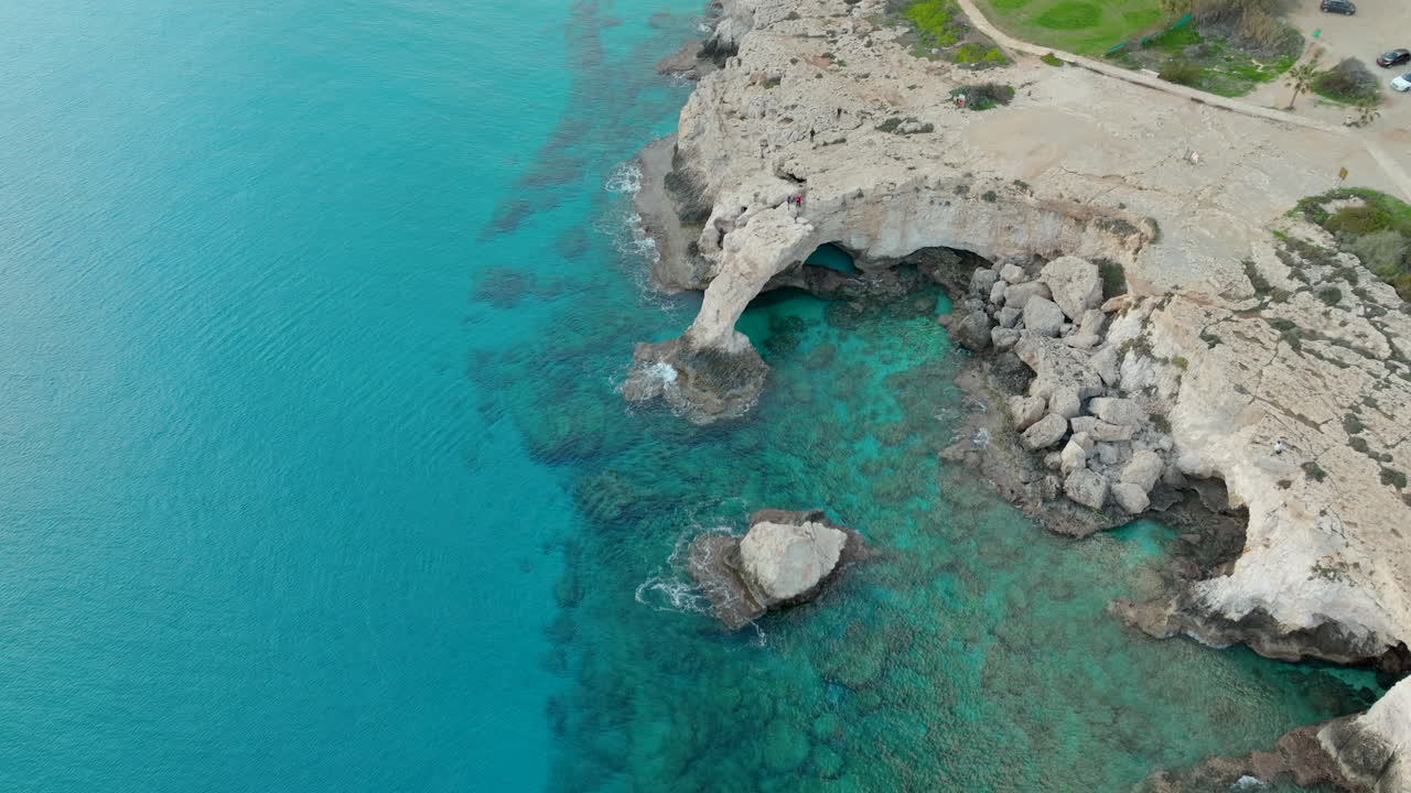vista aérea distante de personas caminando por el puente de los amantes o puente del amor en chipre en un día soleado en el cabo greco, ciudad de ayia napa
