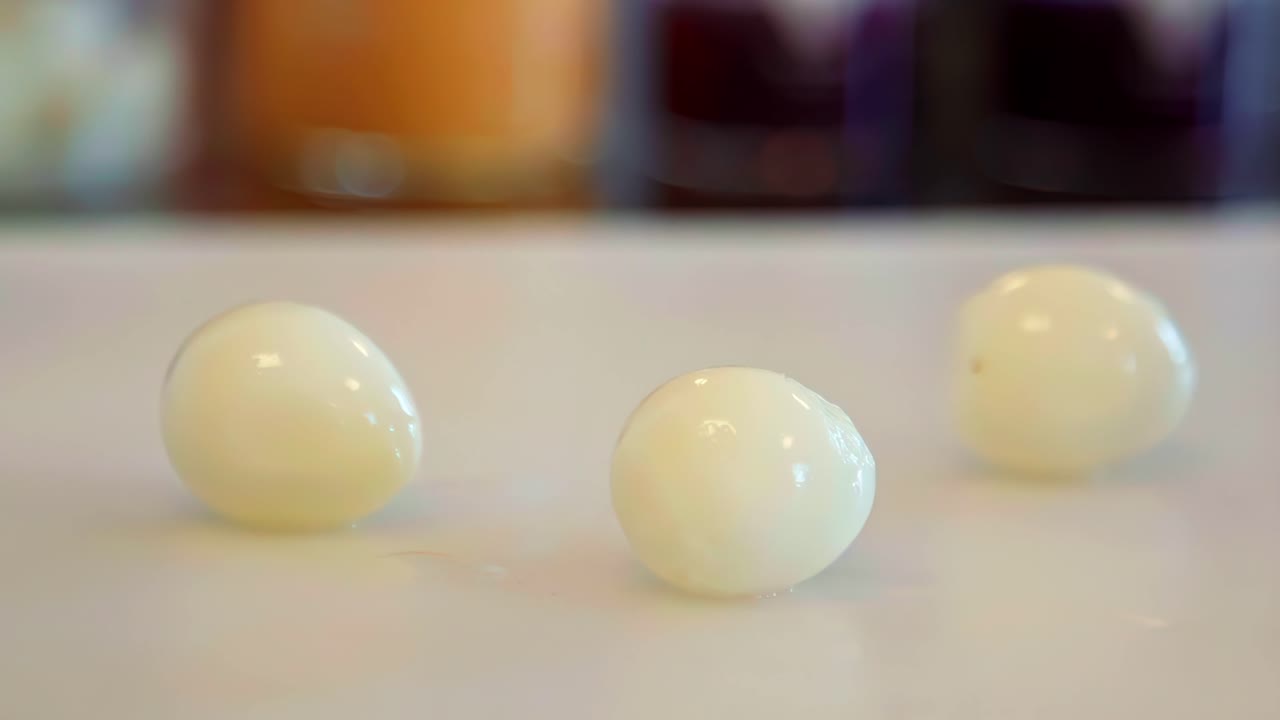 Three peeled, hard-boiled eggs sit on a counterop with a soft-focus background