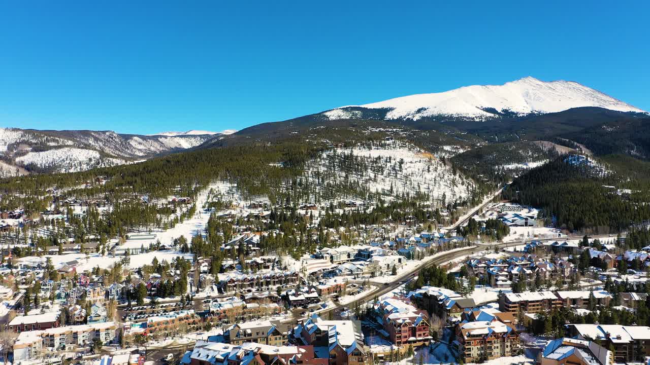 콜로라도주 브레켄리지에 있는 높은 산의 드론 영상, 겨울방학 하이킹을 위해 눈 정상을 향해 도로를 달리는 자동차들