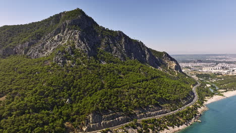 Antalya-Turquía-Antena-V54-Panorámica-Lejos-De-Tünek-Tepe,-A-Lo-Largo-De-La-Carretera-Costera-Que-Captura-Cadenas-Montañosas,-Playa-Topcam-Delimitada-Por-El-Mar-Mediterráneo-Y-La-Isla-Sican---Rodada-Con-Cine-Mavic-3---Julio-De-2022