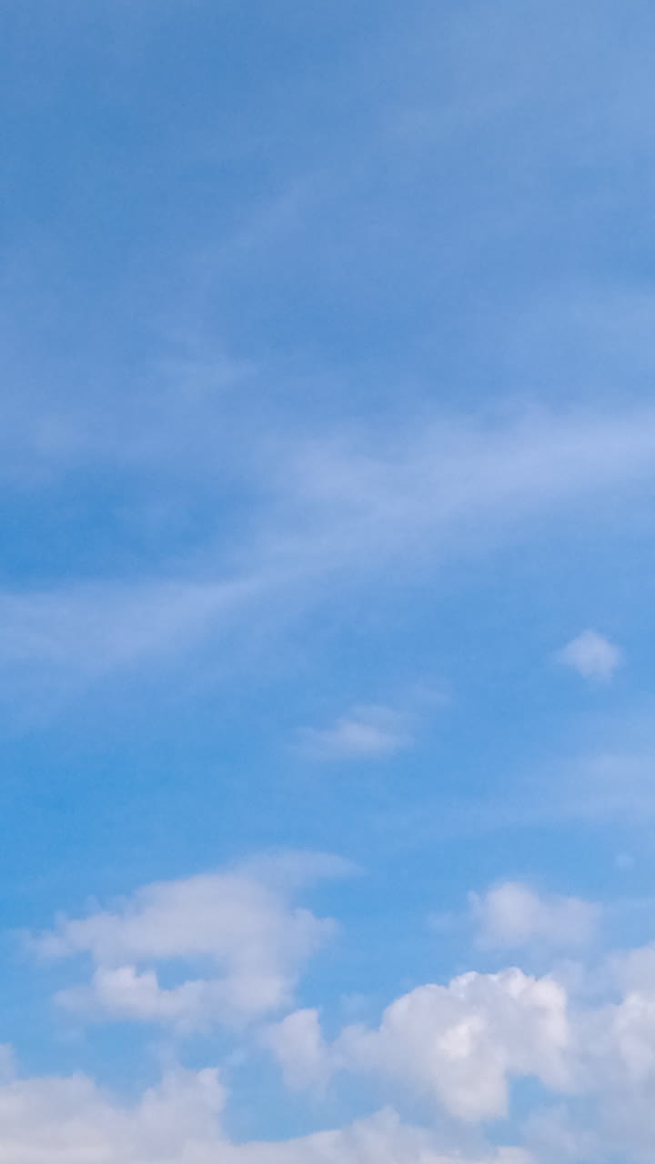 Cirro-cumulus cloudscape covering the horizon. Summer sky with light clouds at daytime. Low angle view. Timelapse. Vertical video