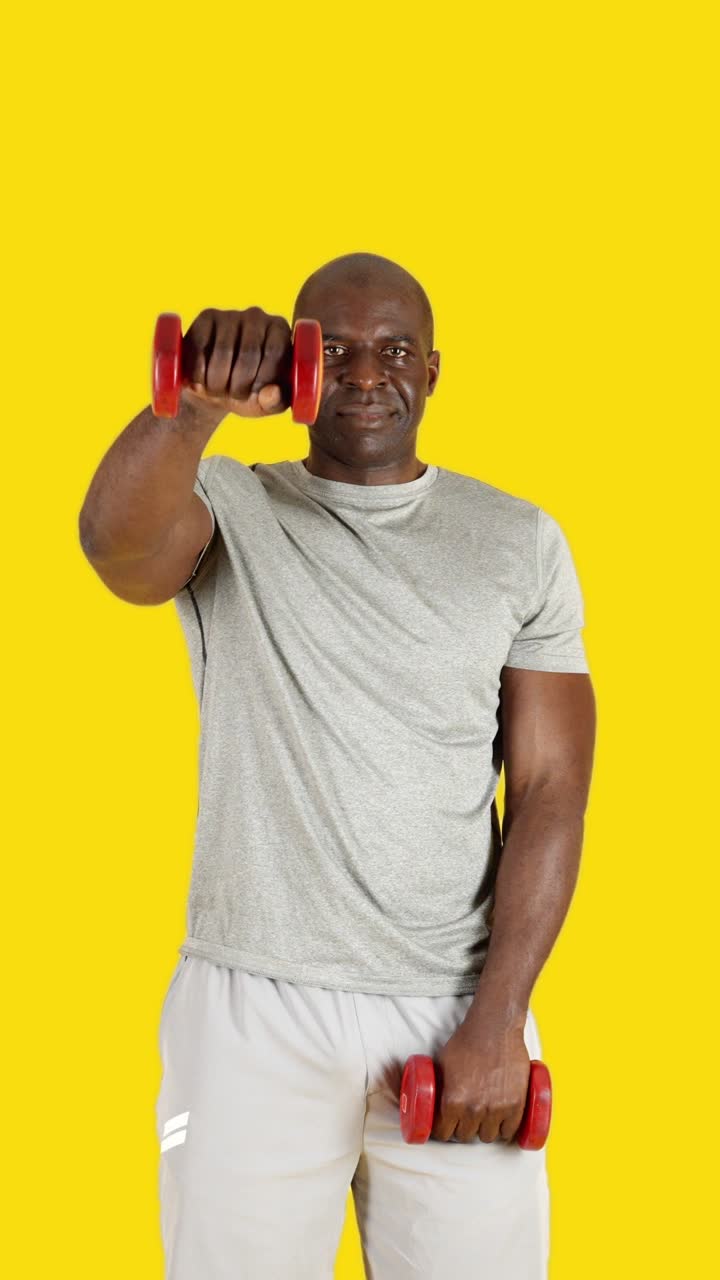 Senior Man Exercising with Dumbbells on Yellow Background