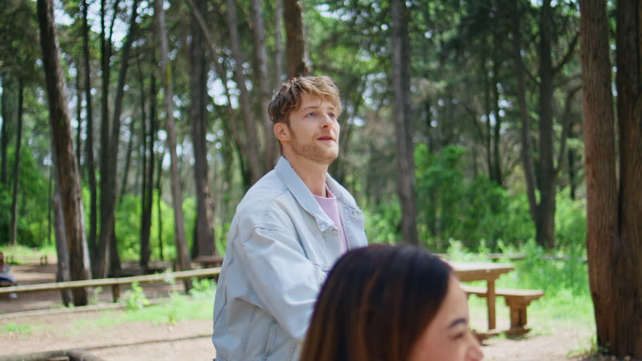 Smiling man juggling vegetables at friendly picnic in summer forest closeup