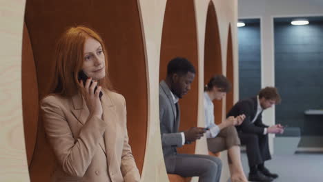 four business colleagues using phones in office