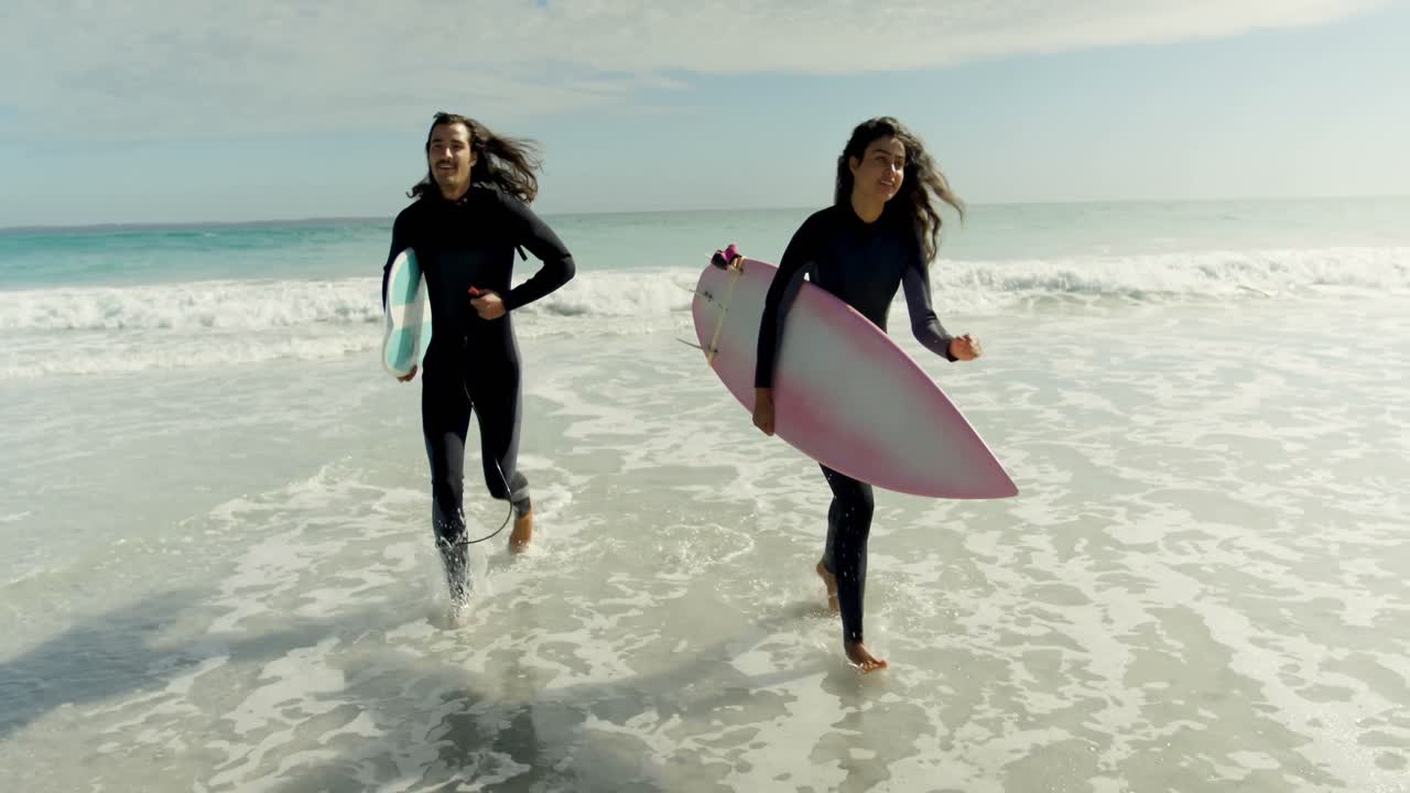 pareja con tabla de surf corriendo en la playa 4k