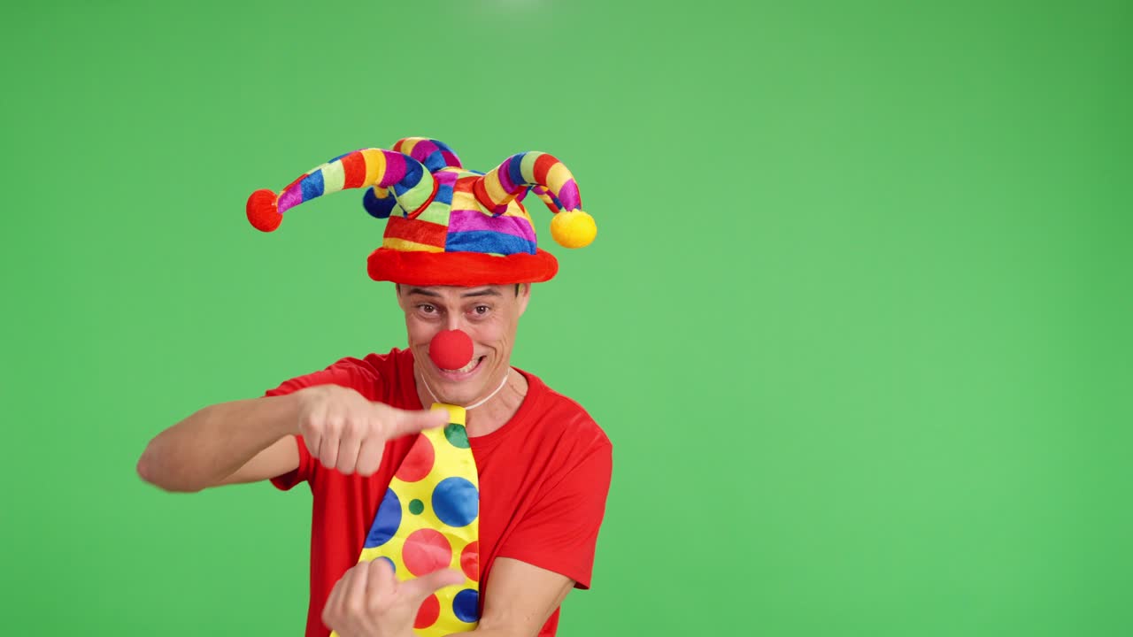 Clown pointing aside on green screen background