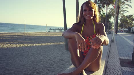 Sexy-young-woman-sitting-waiting-on-a-wall