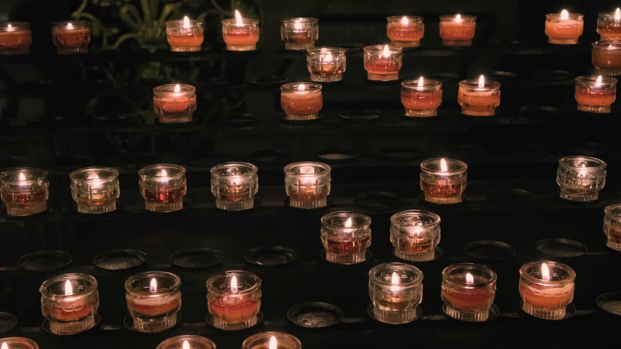 File di candele votive rosse in una chiesa