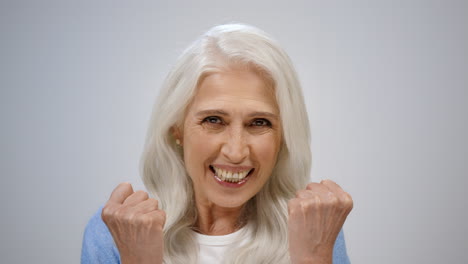 mujer de edad alegre regocijándose en el interior, anciana feliz disfrutando de las noticias en el estudio.