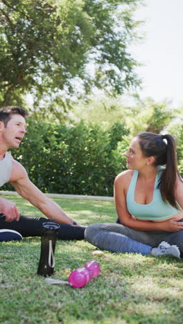 Vertical video of caucasian couple doing yoga and stretching in garden, in slow motion