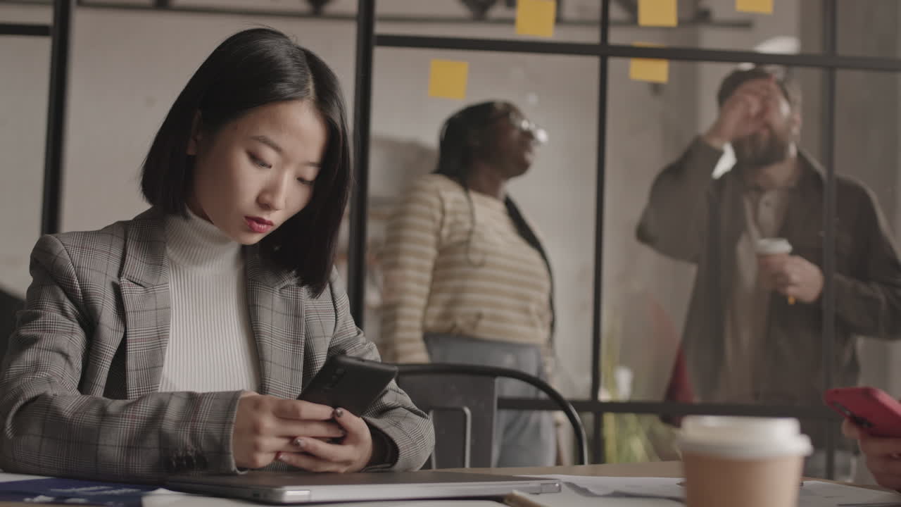 亚洲女商人使用智能手机并交谈。