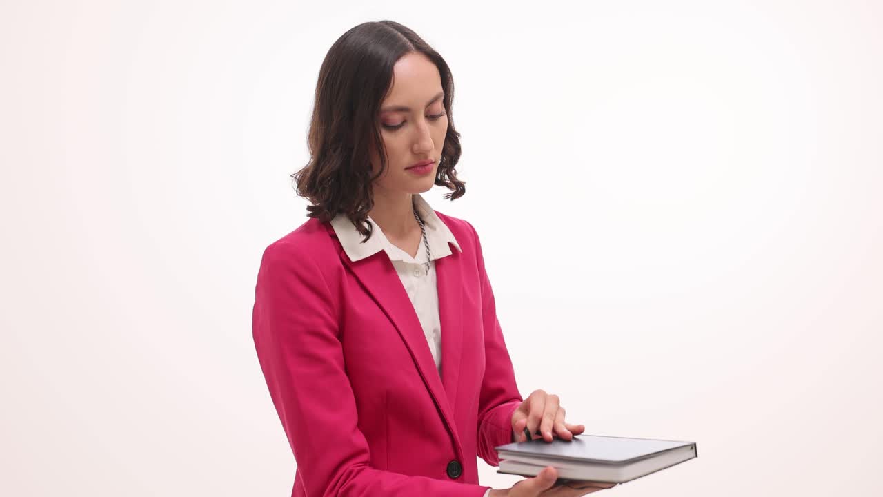 Woman in a pink blazer opening and reading a book