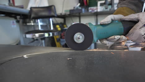 Person-Cutting-Steel-Plate-Using-An-Electric-Grinder-With-Sparks-At-The-Workshop