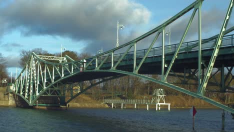 Cars driving over the Oskara Kalpaka Metal Swing Bridge at Liepaja in sunny afternoon, wide shot