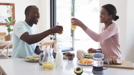 a young african american couple has breakfast in their kitchen