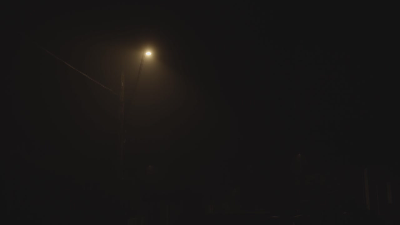 Lit light pole in foggy night. Gimbal, low angle