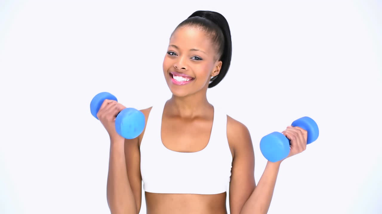 Cheerful model in sportswear exercising with dumbbells