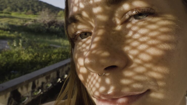 Closeup portrait of beautiful Caucasian glamour woman wearing black nose ring in a summer day with shadow net reflection from metal sunshade on her face