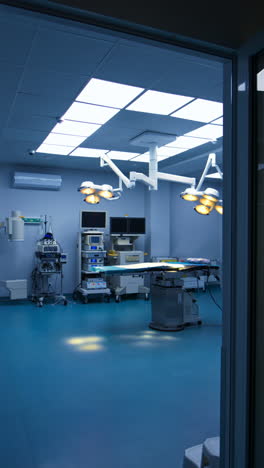 entering the light and spacious surgery room from a dark hall. approaching operational table with lamps switched on over it. advanced equipment at the wall. vertical video