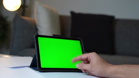 hand scrolling on digital tablet with chroma green screen—ideal for tech, apps, or marketing content with replaceable display