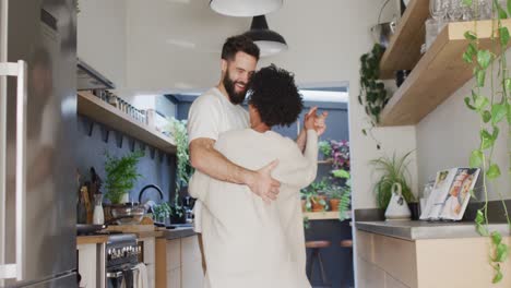 Video-of-happy-diverse-couple-having-fun-dancing-together-in-kitchen