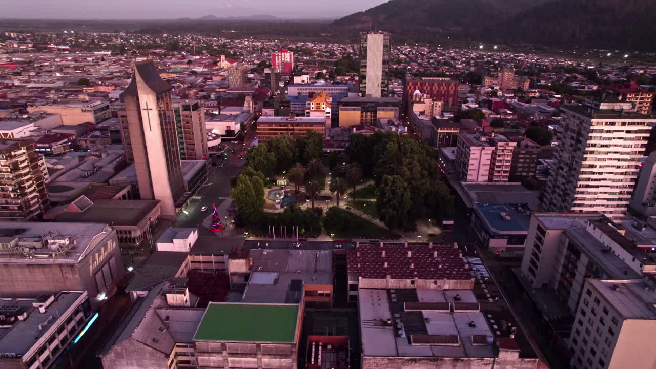 órbita aérea de la plaza de armas anibal pinto y la iglesia catedral de temuco en la hora azul con colores morados y la calle iluminada por la noche, temuco, chile