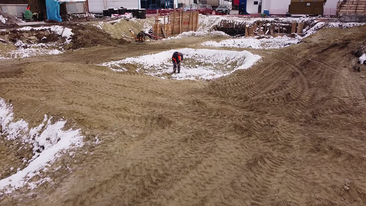 Winter Construction Site with Excavation and Worker