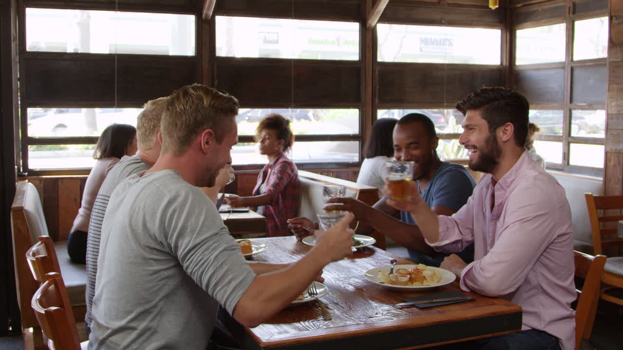 Four male friends making a toast at a table in a restaurant, shot on R3D