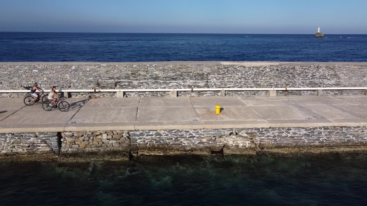 Couple Biking on a Chora of Andros Neimporio Marina Seawall, Slowmotion