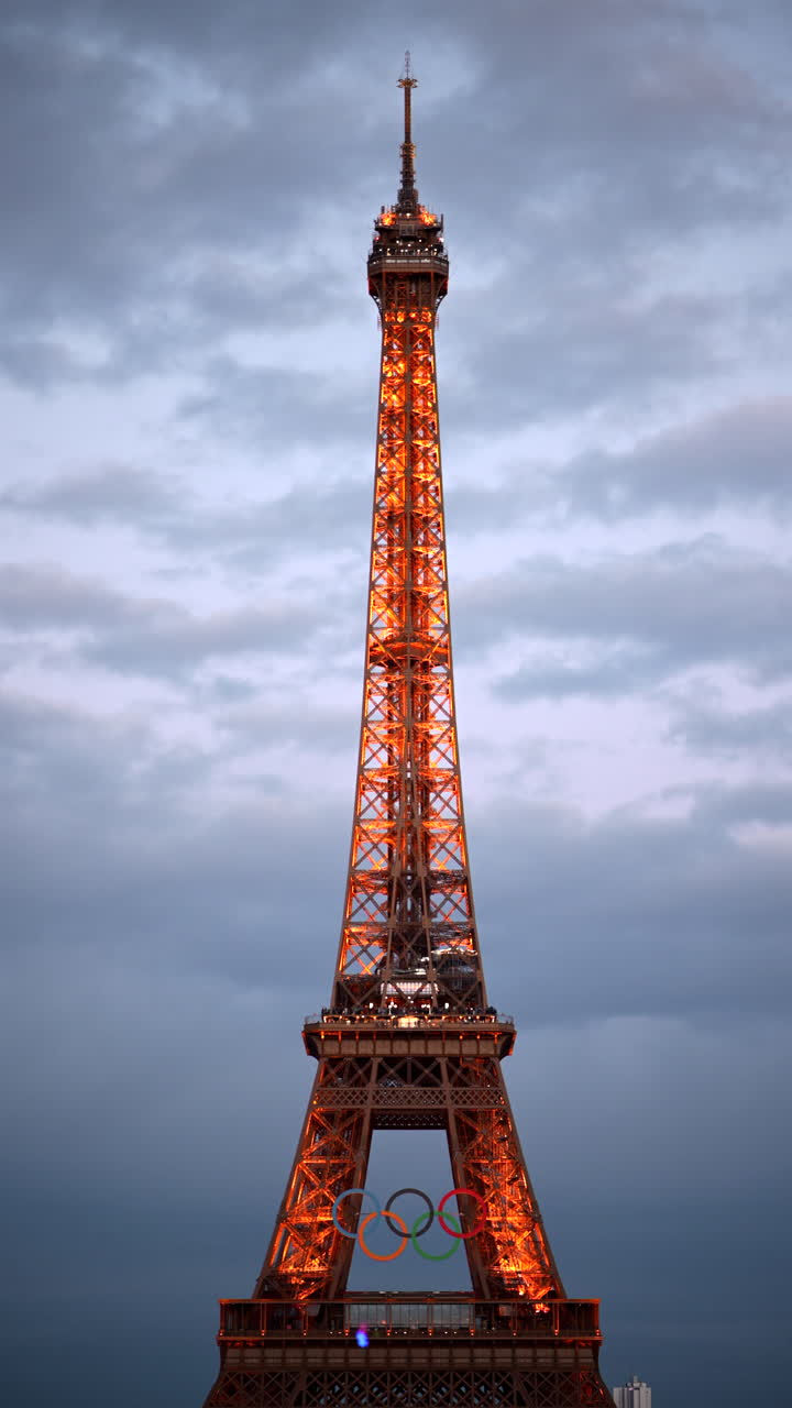 The Eiffel Tower with the Olympic Games sign sparkling in the evening in Paris, France. Vertical