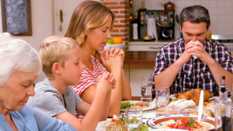 Cute-family-praying-before-eating-dinner