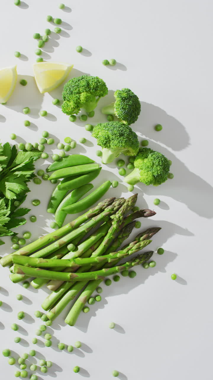 Video verticale di fagioli freschi, prezzemolo, broccoli, aglio e asparagi su sfondo bianco