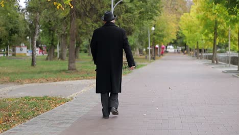 elderly man walking away down a park path