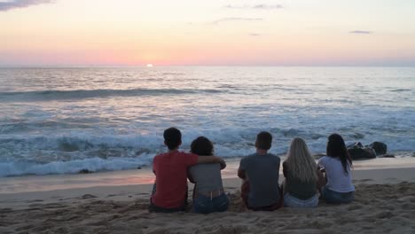 Group-of-friends-sitting-on-the-beach-4k