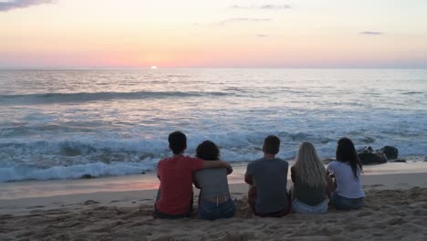 group of friends sitting on the beach 4k