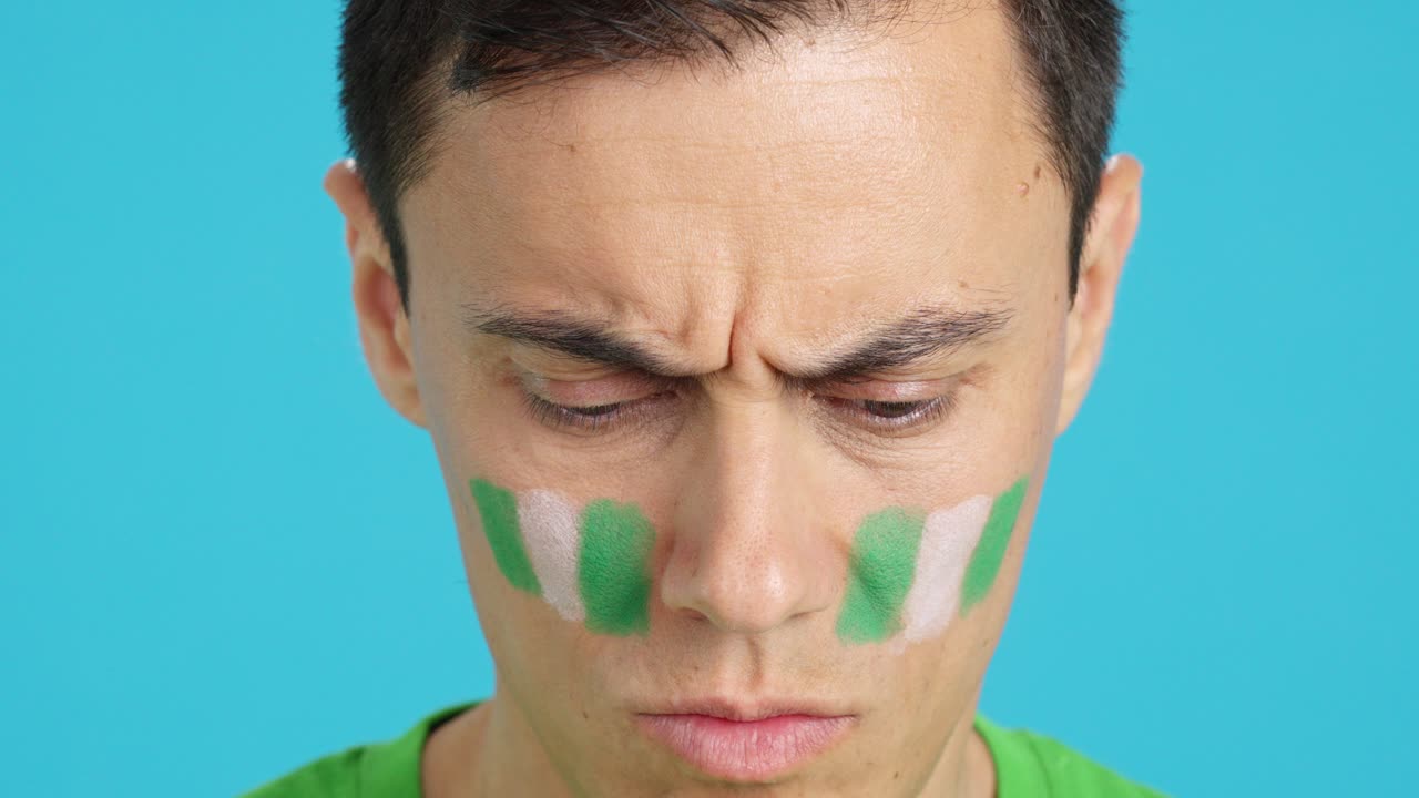 Serious man with a nigerian flag painted on the face