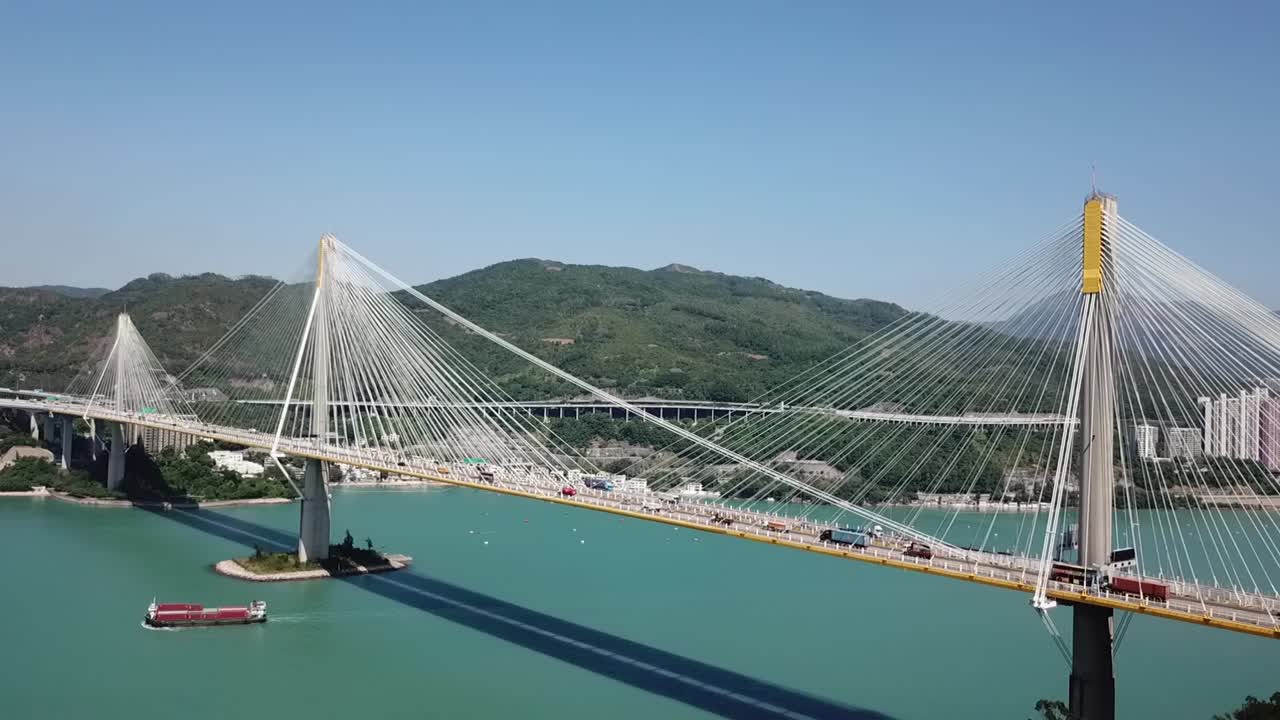 toma aérea, pista en el puente ting kau, ángulos de visión giratorios mirando a través del puente y los edificios y la montaña al fondo.