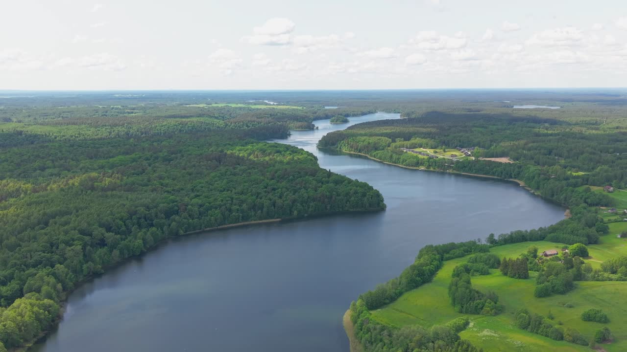 Vista aerea di un fiume serpeggiante circondato da lussureggianti foreste verdi e campagna sotto un cielo estivo luminoso