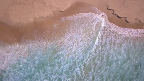 Beautiful-top-aerial-view-of-beach-with-turquoise-ocean-water-and-sea-waves-reaching-shore