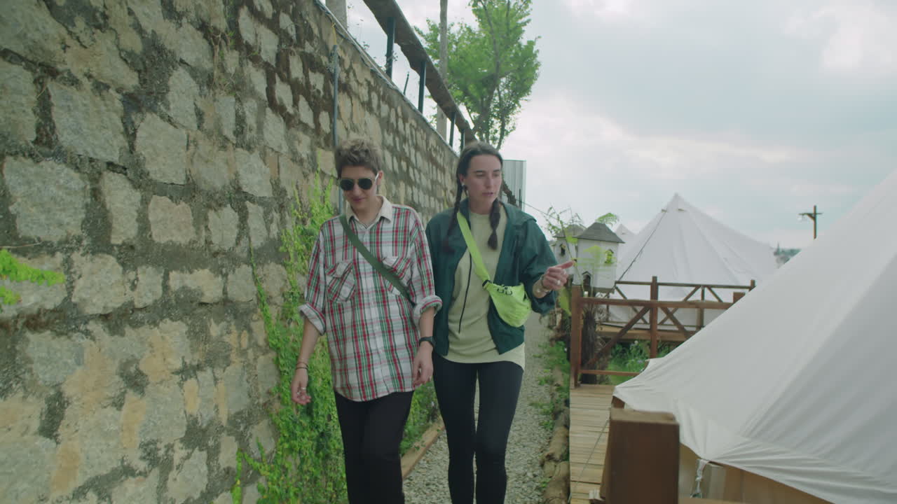 Two Girls Walking through Glamping Resort and Talking