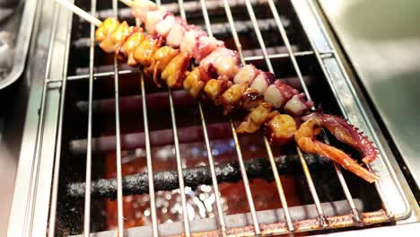 squid skewers being brushed with sauce on grill